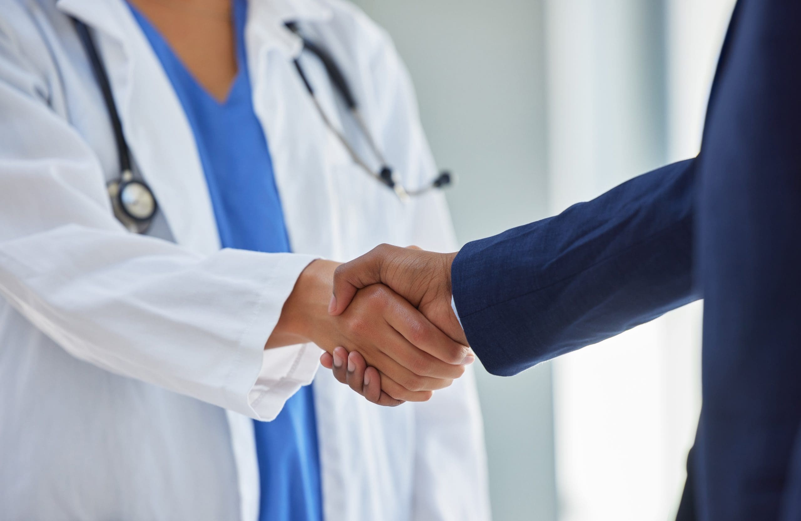 Business handshake and doctor partnership in a hospital with thank you and greeting gesture. Clinic, healthcare and professional deal shaking hands with agreement and contract success for b2b